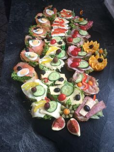 a table topped with lots of different types of sushi on top of each other