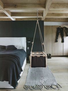 a bed room with a neatly made bed and a hanging chair in the middle of it