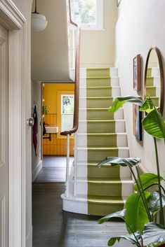 the stairs are painted green and white in this entryway with potted plants on either side