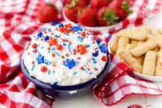 red, white and blue cake in a bowl on a checkered tablecloth with strawberries