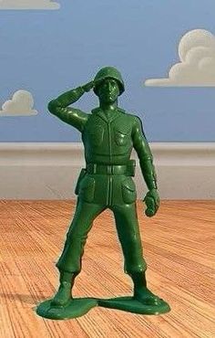 a green toy soldier is standing on the floor