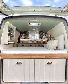 the interior of a camper with its bed and storage compartment open