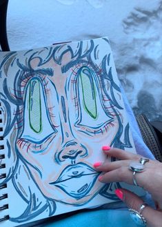 a woman's hand holding up a drawing in front of her face and eyes