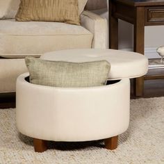 a white ottoman sitting next to a chair and table