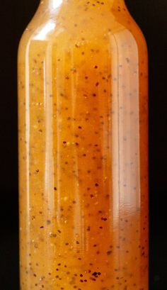 a glass jar filled with yellow liquid sitting on top of a table next to a black background