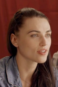 a woman with long brown hair wearing a denim shirt and looking off to the side