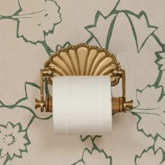 a toilet paper roll is hanging on the wall with a gold scalloped design