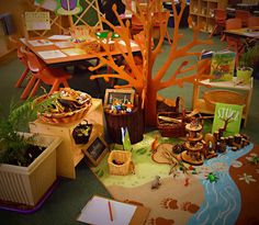 a group of children's toys and books on the floor in front of a tree