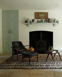 a living room with a fireplace and two chairs in front of it on a rug