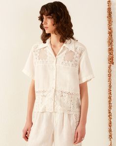 A person with curly brown hair wears the Stevie Picnic Eyelet Shirt White Camp Collar Top With Floral Embroidery, Summer Floral Embroidered Top With Spread Collar, Summer Top With Floral Embroidery And Spread Collar, Daywear Blouse With Camp Collar, Collared Tops With Floral Embroidery For Vacation, Cotton Vacation Blouse With Collar, Spring Bohemian Tops With Camp Collar, Bohemian Spring Tops With Camp Collar, Bohemian Camp Collar Tops For Spring