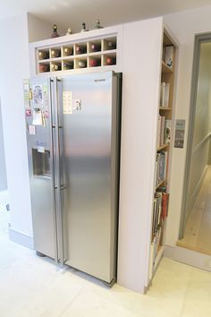 a silver refrigerator freezer sitting inside of a kitchen next to a bookshelf