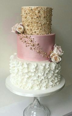 a three tiered cake with pink and white flowers on the bottom, topped with gold sequins