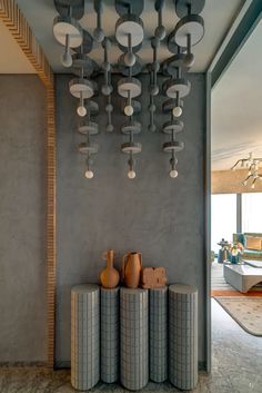 a room filled with vases and lamps hanging from the ceiling next to a wall