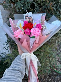 a person holding a bouquet of flowers with pictures on the front and back of it