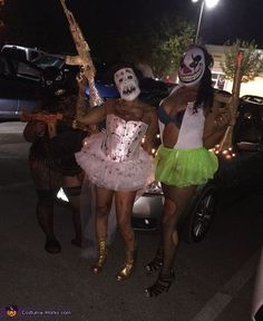 two women dressed up in costumes standing next to each other on the street at night