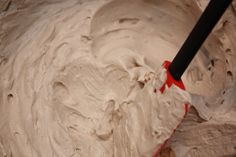 a red spatula in a mixing bowl filled with white cream