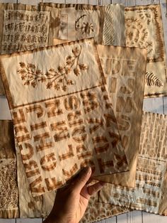 someone is holding up some old quilts on the floor with their hand in front of them