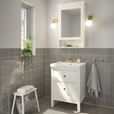 a white sink sitting under a bathroom mirror next to a window with light coming in