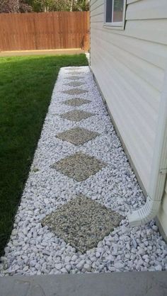 a walkway made out of rocks and gravel next to a house