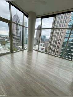 an empty room with wooden floors and large windows looking out on the cityscape