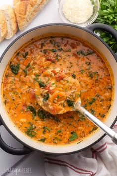 a ladle full of soup with bread and parsley on the side, ready to be eaten