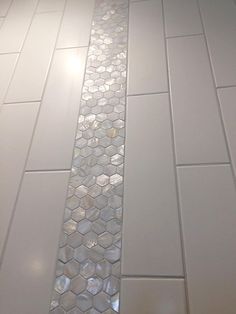 a white tiled bathroom floor with hexagonal tiles on the bottom and one side