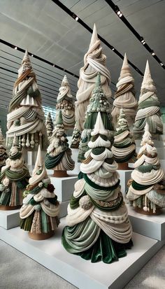 a group of christmas trees sitting on top of white pedestals in front of a ceiling