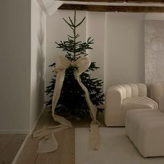 a living room with white furniture and a small christmas tree in the corner on the wall