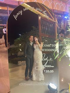 a bride and groom standing in front of a large mirror with the words welcome to our wedding written on it