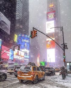 a city street filled with lots of traffic covered in snow and surrounded by tall buildings