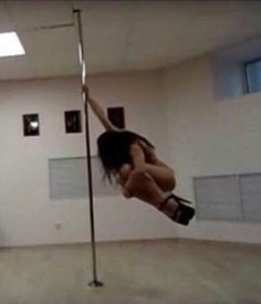 a woman is hanging upside down on a pole in an empty room with no one around