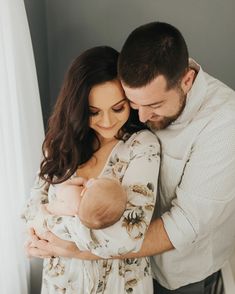 a man and woman holding a baby in their arms