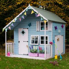 a little blue house with white trim and some decorations on the front porch is decorated with bunting