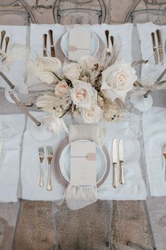 the table is set with silverware and white flowers