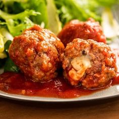 meatballs covered in marinara sauce and cheese on a plate with lettuce