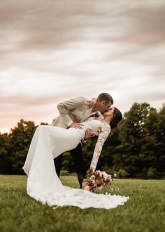 a bride and groom kissing in the grass