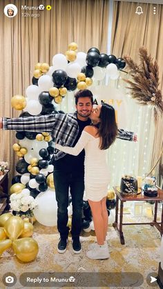 a man and woman standing next to each other in front of balloons