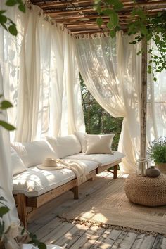 a white couch sitting under a wooden pergol with curtains on top of it's sides