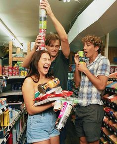 two men and a woman holding up cans in a store