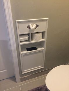 a toilet paper dispenser in the corner of a bathroom with a roll of toilet paper on it