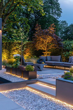 an outdoor living area is lit up at night with lights on the ground and trees in the background