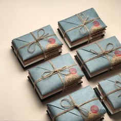 six blue wrapped gift boxes tied with twine and twine string on top of each other