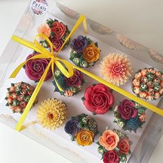 a box filled with cupcakes covered in flowers