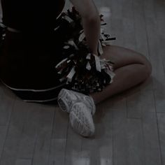 a woman sitting on the floor with some cheerleader's pom poms