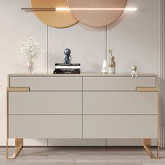 a white dresser with gold accents in front of a round mirror on the wall above it