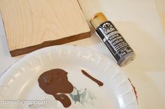 a paper plate with some paint on it next to a wooden board and glue bottle