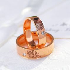 two gold wedding rings sitting on top of each other