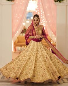 a woman in a yellow and red lehenga poses for the camera with her hands on her hips