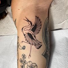 a tattoo on the leg of a person with a bird and flowers around her arm