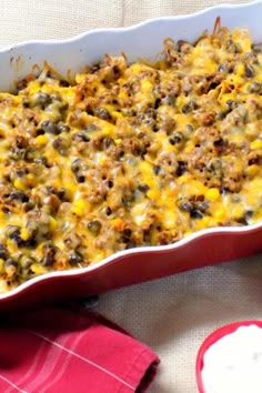 a casserole dish with meat and cheese in it next to a red napkin